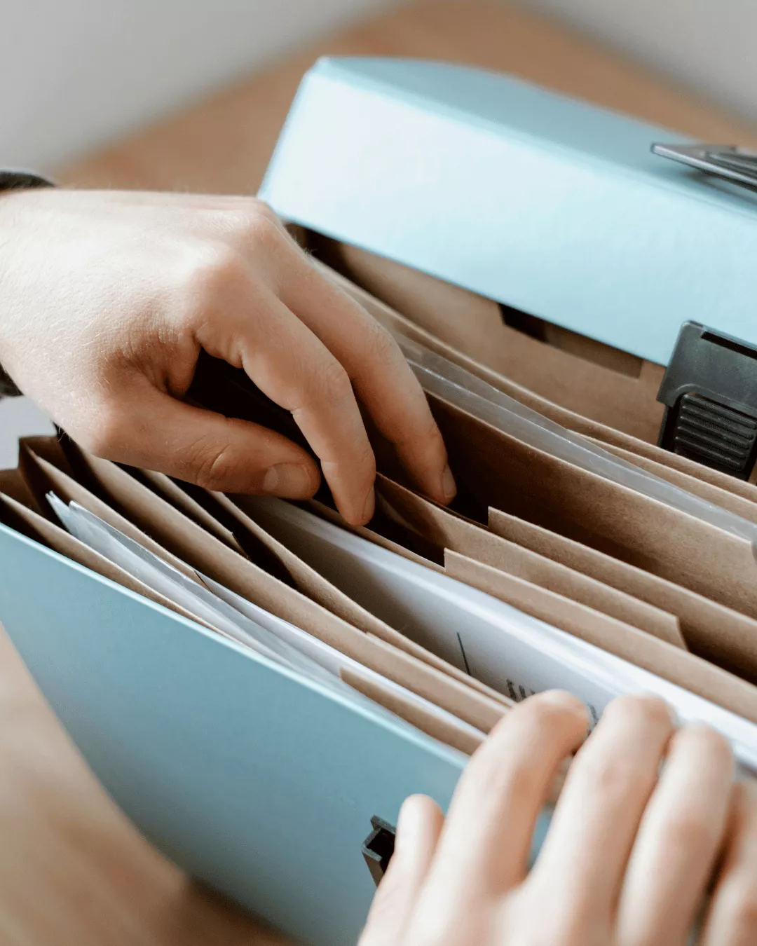 A close up shot of hands sifting through manila folders and documentation.